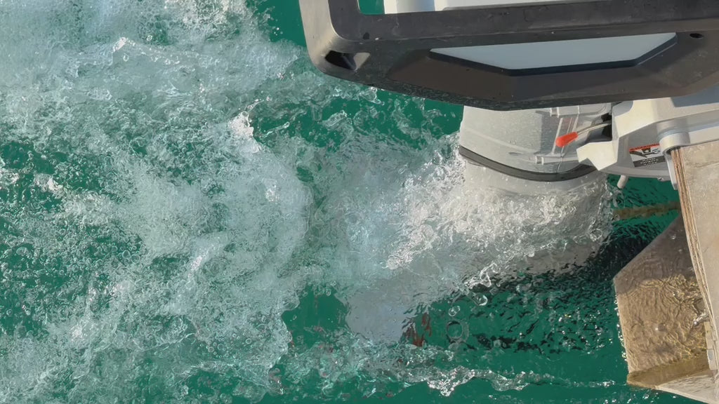 Torqeedo electric outboard fitted with a V4A cavitation plate, running in turquoise water filmed from above the surface.